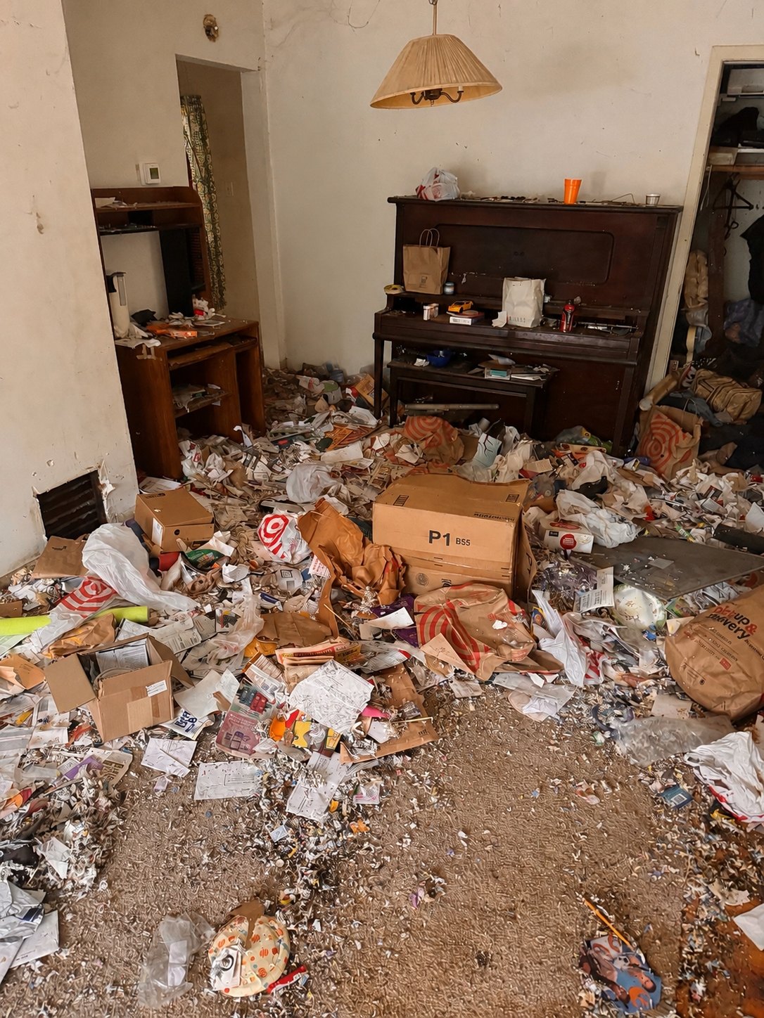 The same living room piled high with furniture and clutter before removal